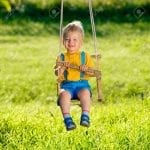 Rural scene with toddler boy swinging outdoors.