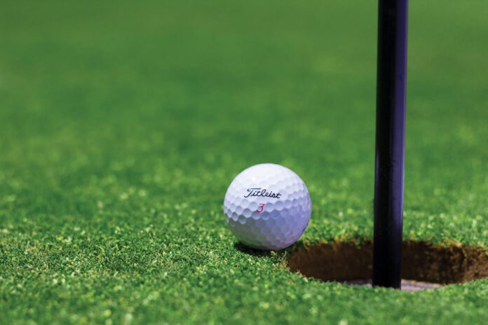 Golf ball next to the hole.