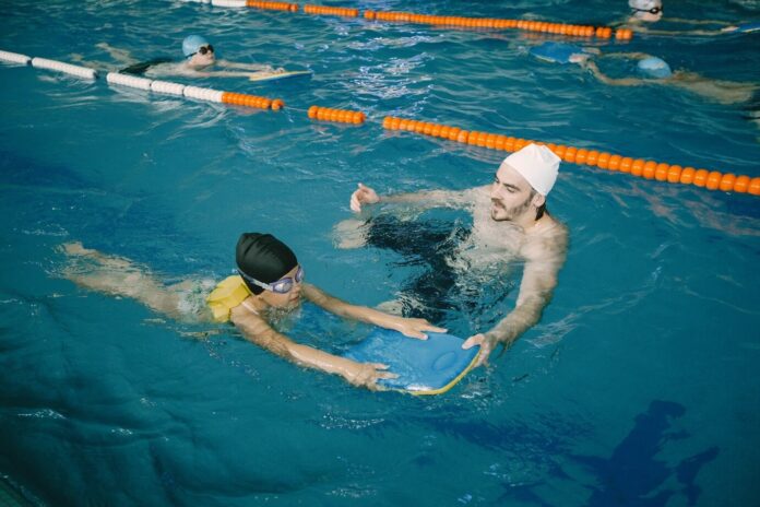 men giving swimming lessons to kid
